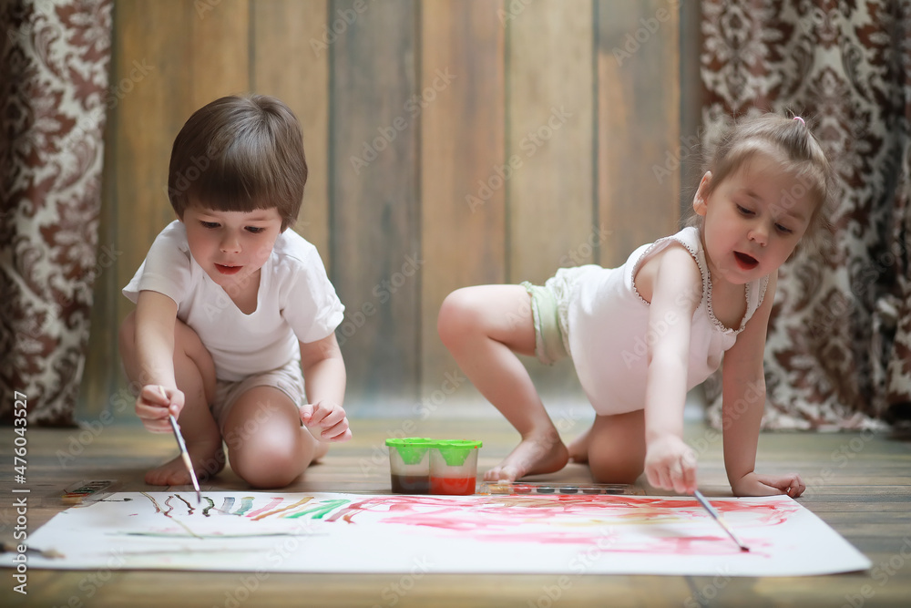 Little children paint on a large sheet of paper Little children paint on a large sheet of paper