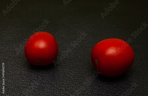 two fresh red tomatoes lying on a black background