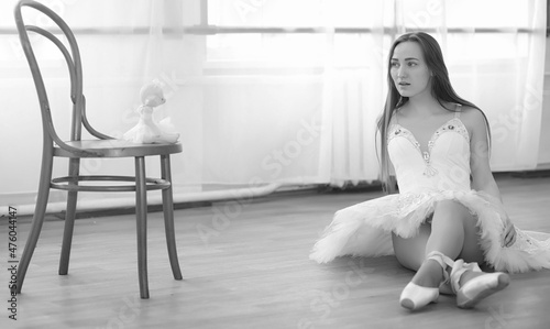 Young ballet dancer on a warm-up. The ballerina is preparing to perform in the studio. A girl in ballet clothes and shoes kneads by the handrails.