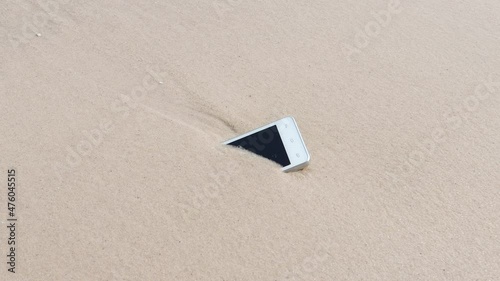 White Mobile phone on sand at beach concept electronic waste