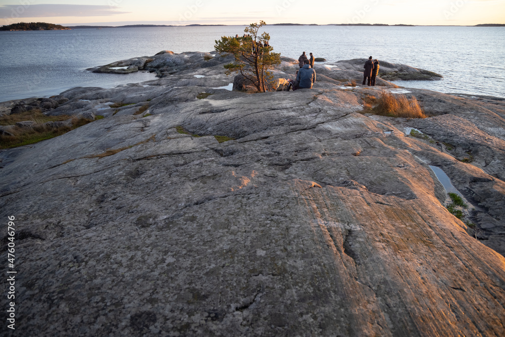 People walking on a rocky shore in Bjorno nature reserve at Baltic sea. Beautiful natural Scandinavian landscape on Sunny late autumn or winter day in Sweden, Stockholm archipelago 2021.12.17
