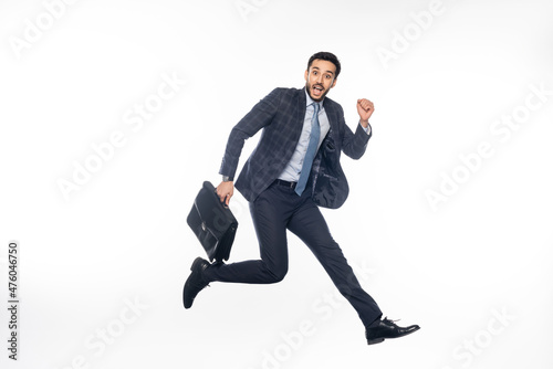 positive businessman in suit jumping with briefcase on white.