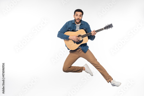 happy man levitating while playing acoustic guitar on white.