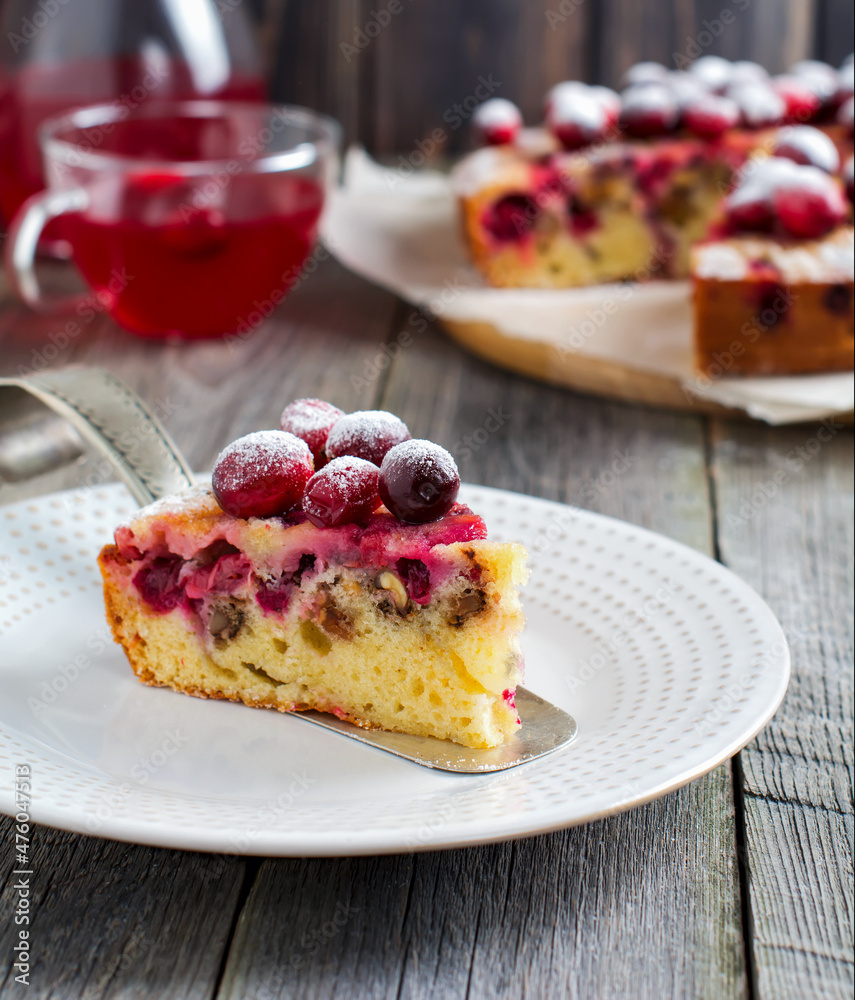 Slice of homemade cranberry cake with walnouts, berries and powdered sugar on a ceramic plate. Space for text. Rustic style. Selective focus. Slice of homemade cranberry cake with walnouts, berries and powdered sugar on a ceramic plate. Space for text. Rustic style. Selective focus.