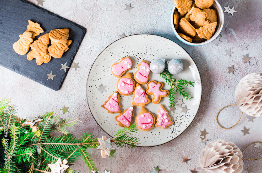 Freshly baked Christmas cookies with pink icing on a plate on a decorated table. Festive treat. Top view. Freshly baked Christmas cookies with pink icing on a plate on a decorated table. Festive treat. Top view.