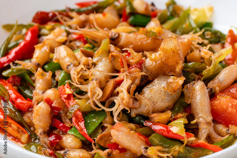 Spicy Stir Fried Squid or Tumis Cumi Pedas is Indonesian traditional food, especially in javanese. served on plate and isolated gray background. Spicy Stir Fried Squid or Tumis Cumi Pedas is Indonesian traditional food, especially in javanese. served on plate and isolated gray background.
