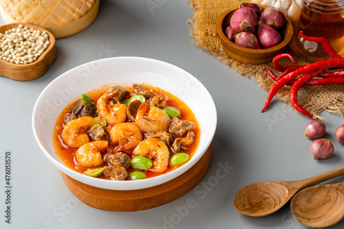Chili prawns or Sambal Udang with petai or pete in white plate on gray background. Indonesia cuisine food. 