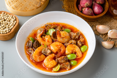 Chili prawns or Sambal Udang with petai or pete in white plate on gray background. Indonesia cuisine food. 