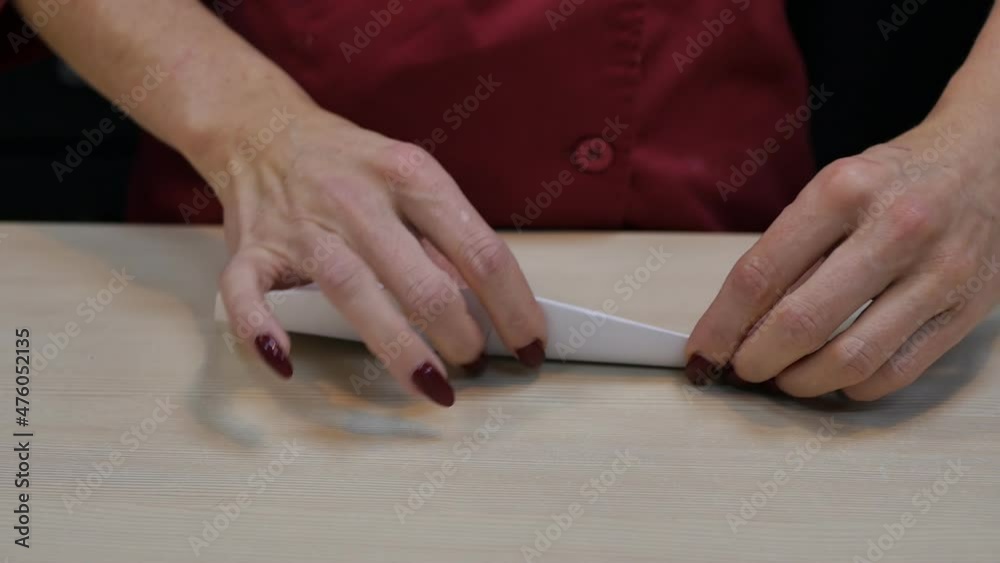 woman with her hands with red manicure bends origami paper on the table. Women's hands took scissors and make a figurine. Paper figurine. woman with her hands with red manicure bends origami paper on the table. Women's hands took scissors and make a figurine. Paper figurine.