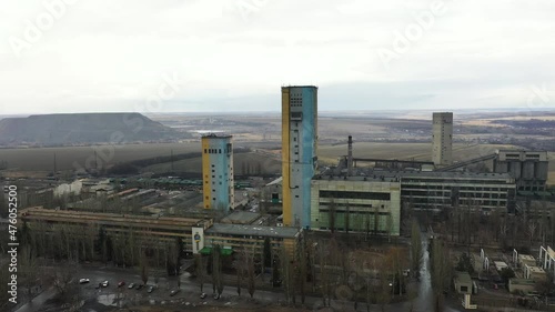 Old coal mine elevator and slag heaps on a cloudy day. Vintage coal mining shaft building, weathered factory and constructions. Fossil fuel and minerals mining heavy industry landscape with terrikons. photo