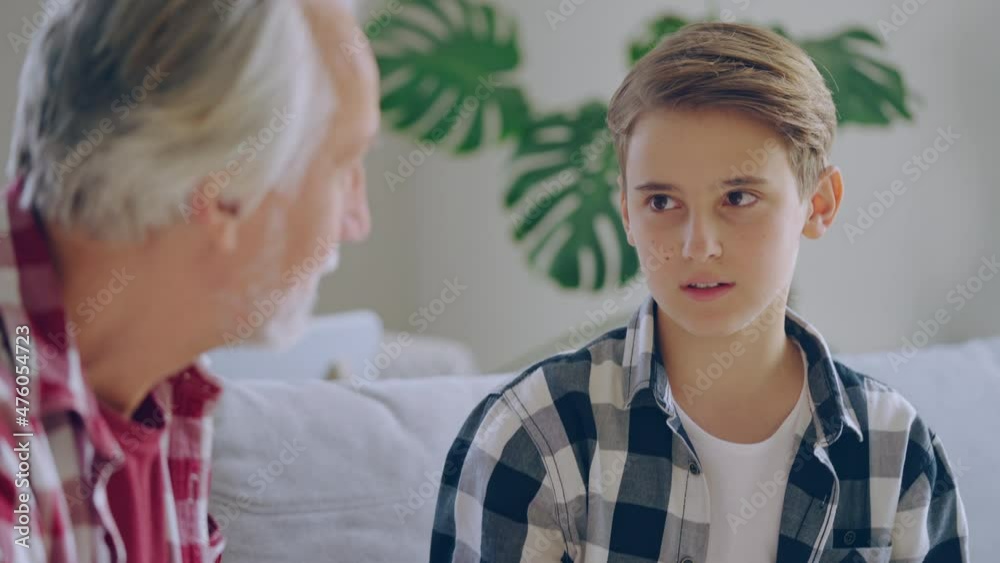 Happy teen boy enjoying conversation with grandfather, family communication