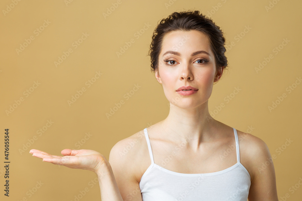 Portrait of a Beautiful Brunette Woman with perfect skin. Spa Girl showing empty copy space on the open hand palm for text. Proposing a product. Gestures for advertisement Beauty Spa. Portrait of a Beautiful Brunette Woman with perfect skin. Spa Girl showing empty copy space on the open hand palm for text. Proposing a product. Gestures for advertisement Beauty Spa.