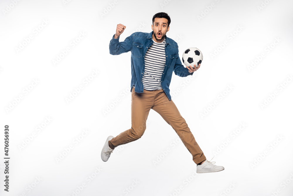 Fototapeta premium worried man levitating while holding soccer ball and cheering on white.