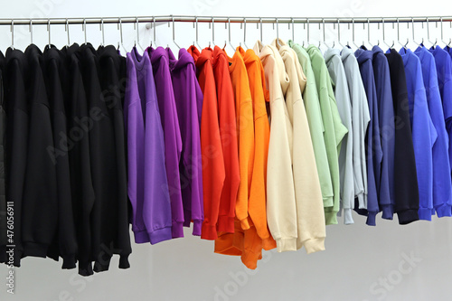 The clothes on the hanger are of different colors, all the colors of the rainbow. Clothes are hung in colors with different tones, shopping in a shopping mall