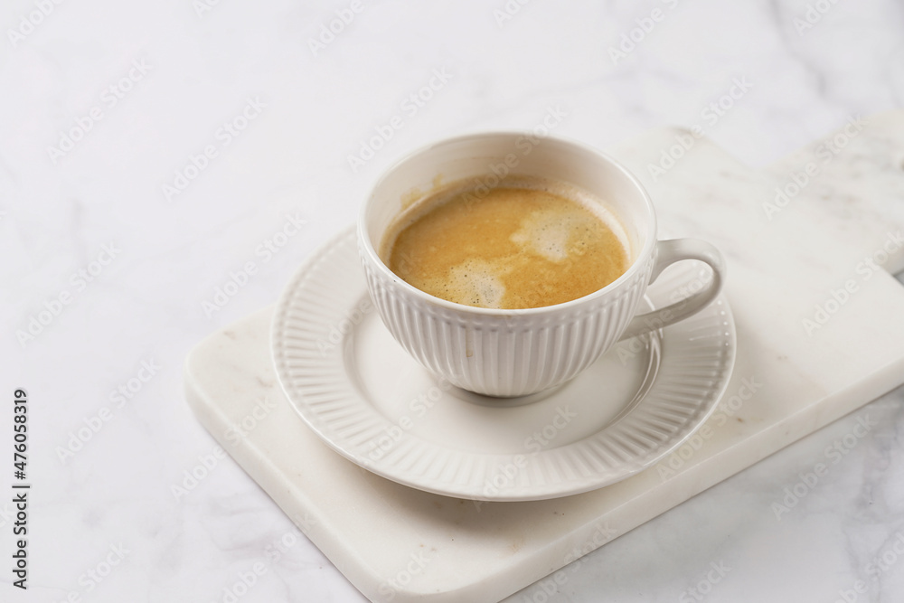 a white porcelain cup with coffee with milk on a marble board on a white table a white porcelain cup with coffee with milk on a marble board on a white table