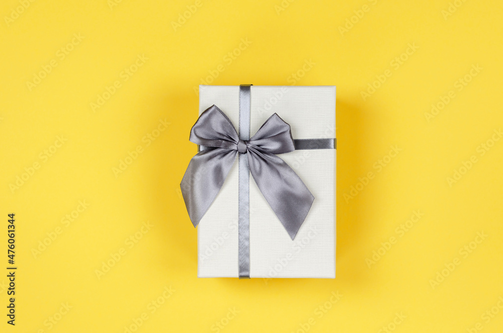 Beige gift box on yellow background, top view Beige gift box on yellow background, top view