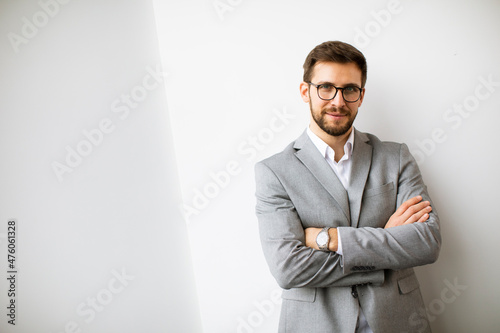 Young modern businessman standing by the wall in the office