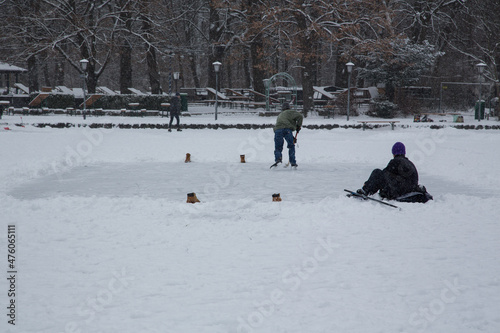 Winter landscape idyllic scene at the frozen lake in the English Garden park, Munich, Germany on a cloudy winter day with people walking, ice skating or playing ice hockey photo