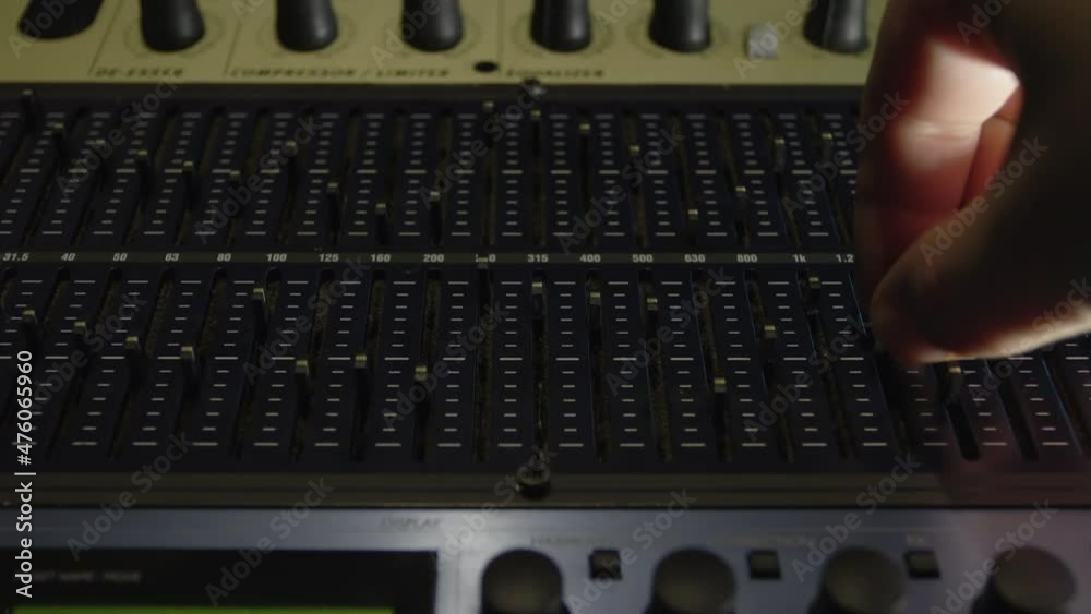 The sound engineer at the disco adjusts the analog equalizer. He moves the sliders of the device and thereby changes the frequency response of the sound. Setting up high-quality sound. The sound engineer at the disco adjusts the analog equalizer. He moves the sliders of the device and thereby changes the frequency response of the sound. Setting up high-quality sound.