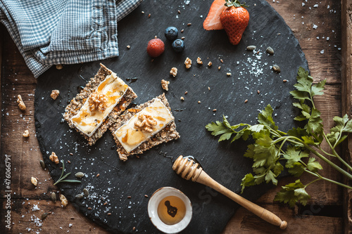 Deliciosas tostadas de pan crujiente de centeno estilo Sueco con queso, almendras y miel, presentadas en pizarra negra 