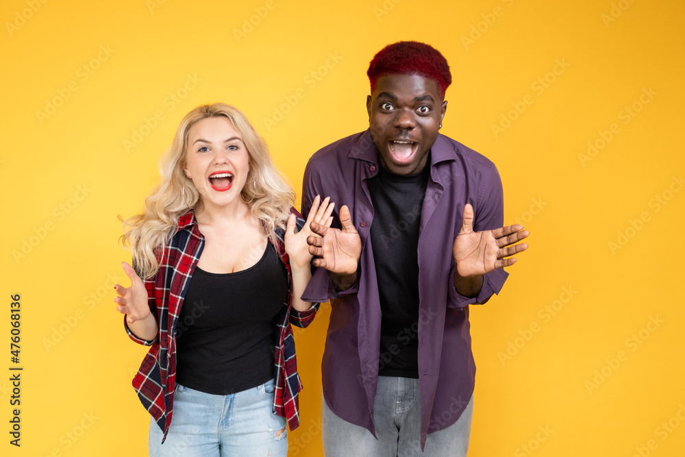 Amazed couple. Unexpected surprise. Wow reaction. Multiethnic friendship. Multiracial excited happy people man woman screaming in joy isolated on yellow background. Amazed couple. Unexpected surprise. Wow reaction. Multiethnic friendship. Multiracial excited happy people man woman screaming in joy isolated on yellow background.