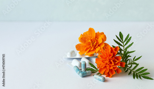 Vitamins. Dietary supplement capsules of Marigold flowers on white background. Concept: vision improvement, eye health care, phytotherapy. Selective focus. Copy space for text. Closeup photo