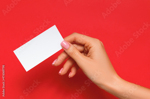 Female hand holding blank card on isolated red background