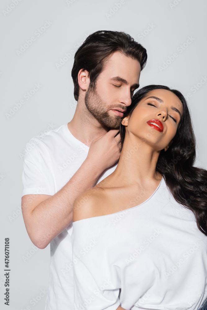man with closed eyes touching neck of passionate woman with bare shoulder isolated on grey. man with closed eyes touching neck of passionate woman with bare shoulder isolated on grey.