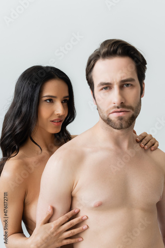 sexy brunette woman embracing shirtless man looking at camera isolated on grey.