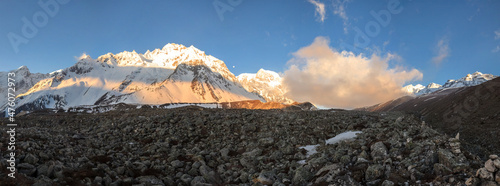 Panorama of snowy mountains near Larke Pass in Himalayas lightened by sunrise
