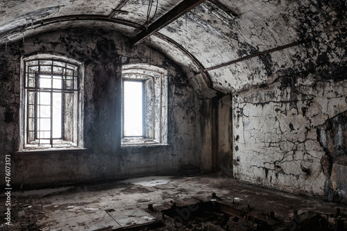 casemate of an abandoned fort  illuminated by daylight through a pair of barred windows