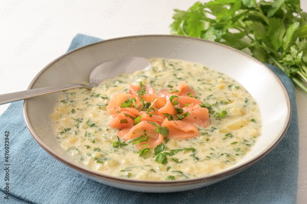 Vegetable cream soup from parsley and potatoes served with salmon strip garnish in a plate on a blue napkin, selected focus, narrow depth of field Vegetable cream soup from parsley and potatoes served with salmon strip garnish in a plate on a blue napkin, selected focus, narrow depth of field
