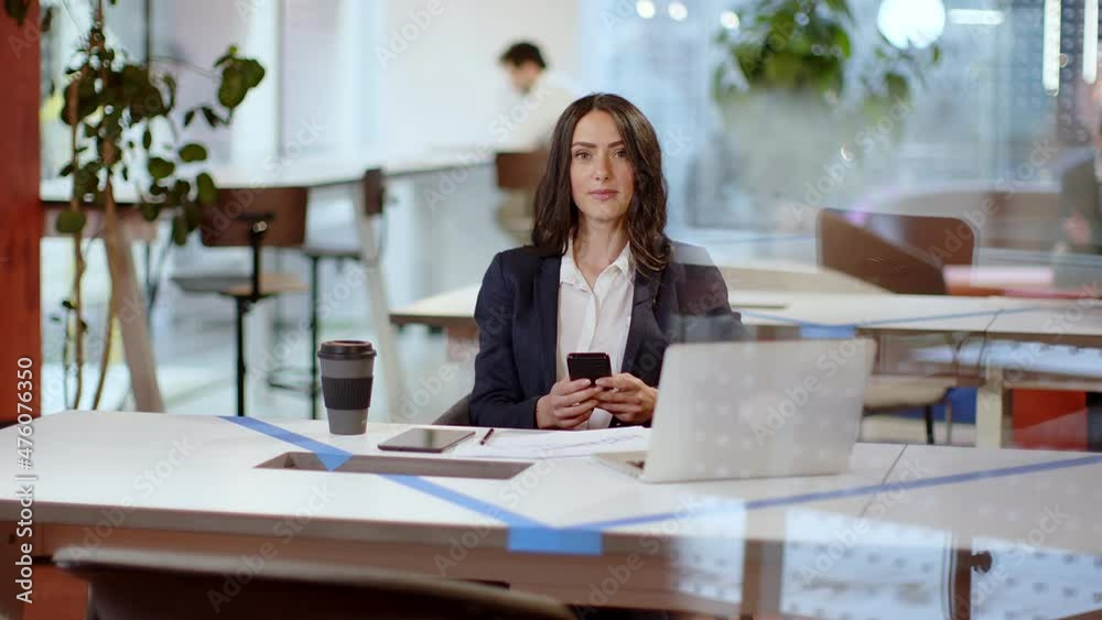 Businesswoman sitting at office desk reading text message Businesswoman sitting at office desk reading text message