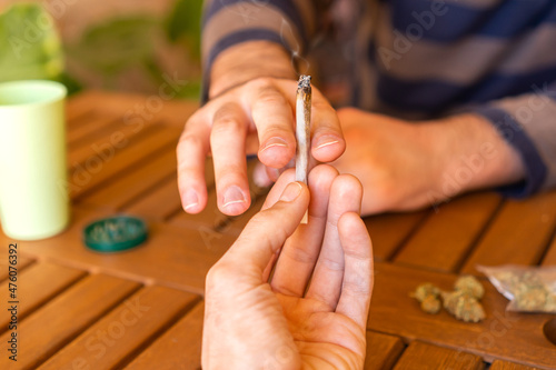 People sitting on a table during a party sharing a cannabis joint.