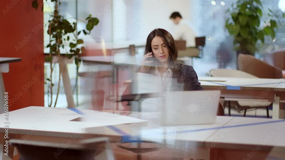 Businesswoman sitting at office desk making a phone call Businesswoman sitting at office desk making a phone call