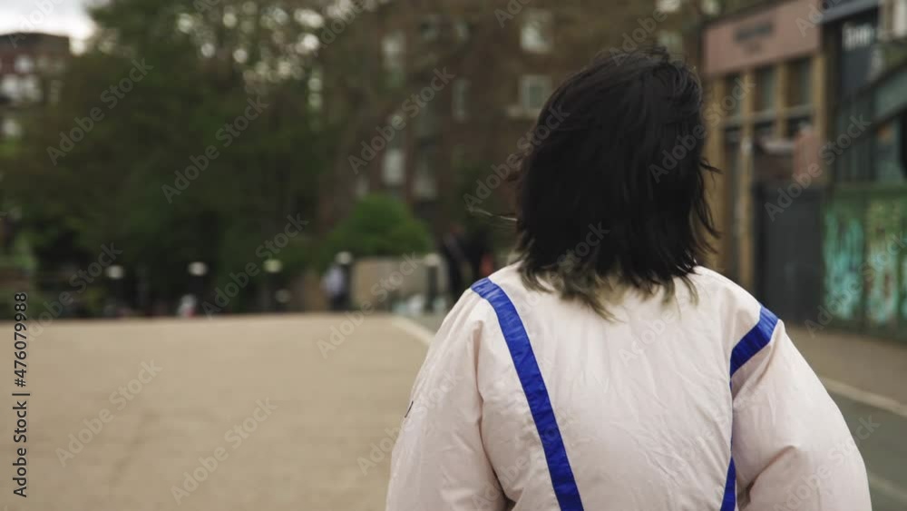 Black haired woman walking in the street looking around Black haired woman walking in the street looking around
