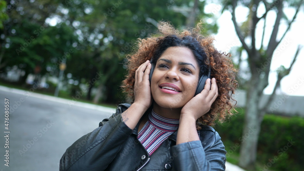 Woman listening to good news podcast wearing headphone outside in street