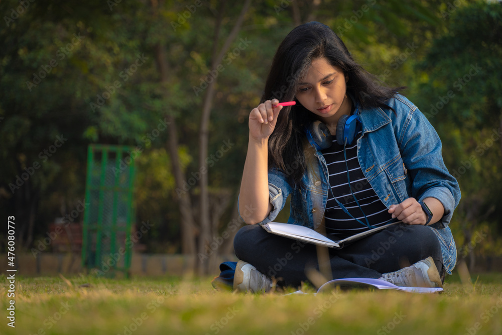 Obraz premium Indian student at college campus full size image reading books and watching camera