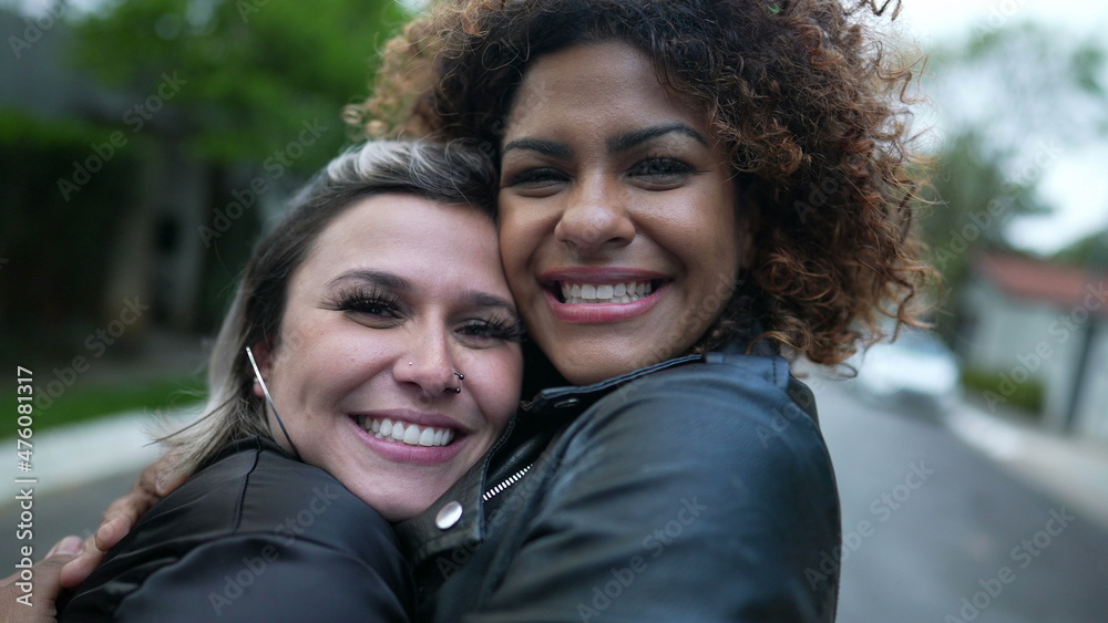 Two diverse female friends hugging each other cheek to cheek Two diverse female friends hugging each other cheek to cheek