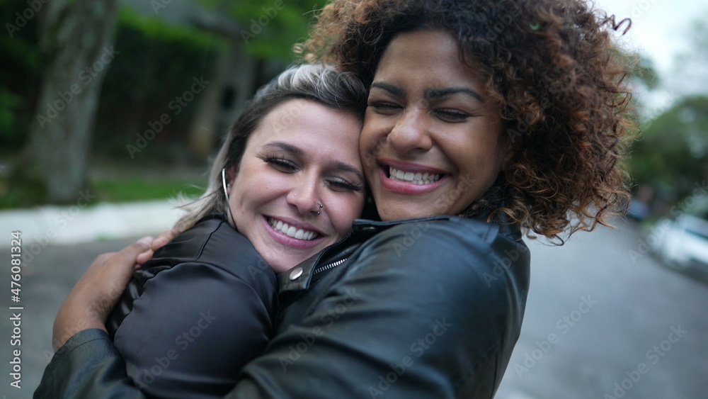 Two diverse female friends hugging each other cheek to cheek