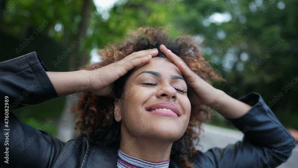 Carefree black woman playing with curly hair outside in street Carefree black woman playing with curly hair outside in street