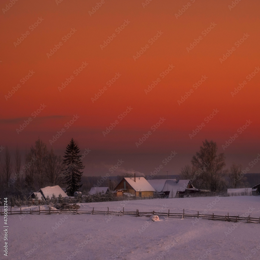 small village on a hill under the snow on the background of a sunset in winter