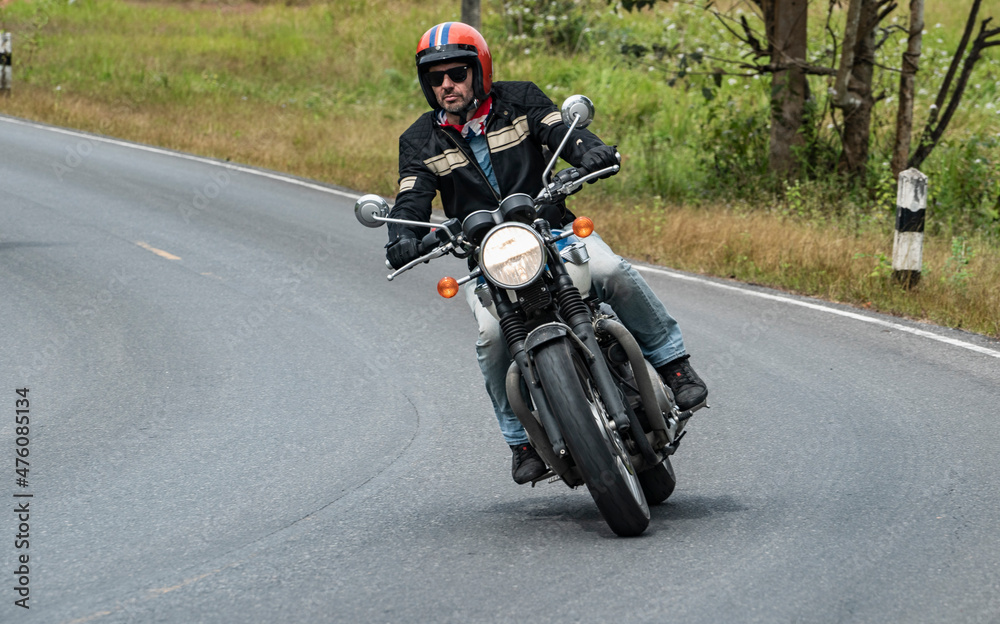 man riding his classic motorcycle at Khao Yai national park man riding his classic motorcycle at Khao Yai national park