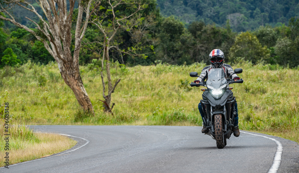 man riding his adventure motorcycle at Khao Yai national park man riding his adventure motorcycle at Khao Yai national park