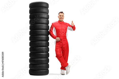 Full length portrait of a racer leaning on a pile of tires and gesturing a thumb up sign © Ljupco Smokovski