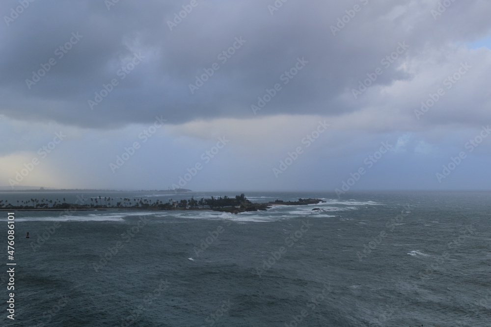Stormy ocean with cloudy sky, with island in a background, view from Castillo San Felipe del Morro, Puerto Rico - obrazy, fototapety, plakaty 
