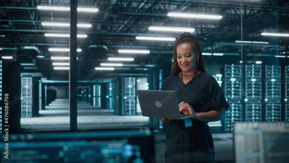 Portrait of African American Female IT Specialist Using Laptop, Standing in Data Center. Infrastructure Architect Works on Web Services. Cloud Computing, Server Analytics, Cyber Security Maintenance
