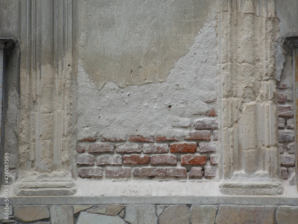 Background of an old brick wall and classical decoration illuminated by the sun. Texture on the surface of worn plaster and stone on a sunny facade wall. Background of an old brick wall and classical decoration illuminated by the sun. Texture on the surface of worn plaster and stone on a sunny facade wall.