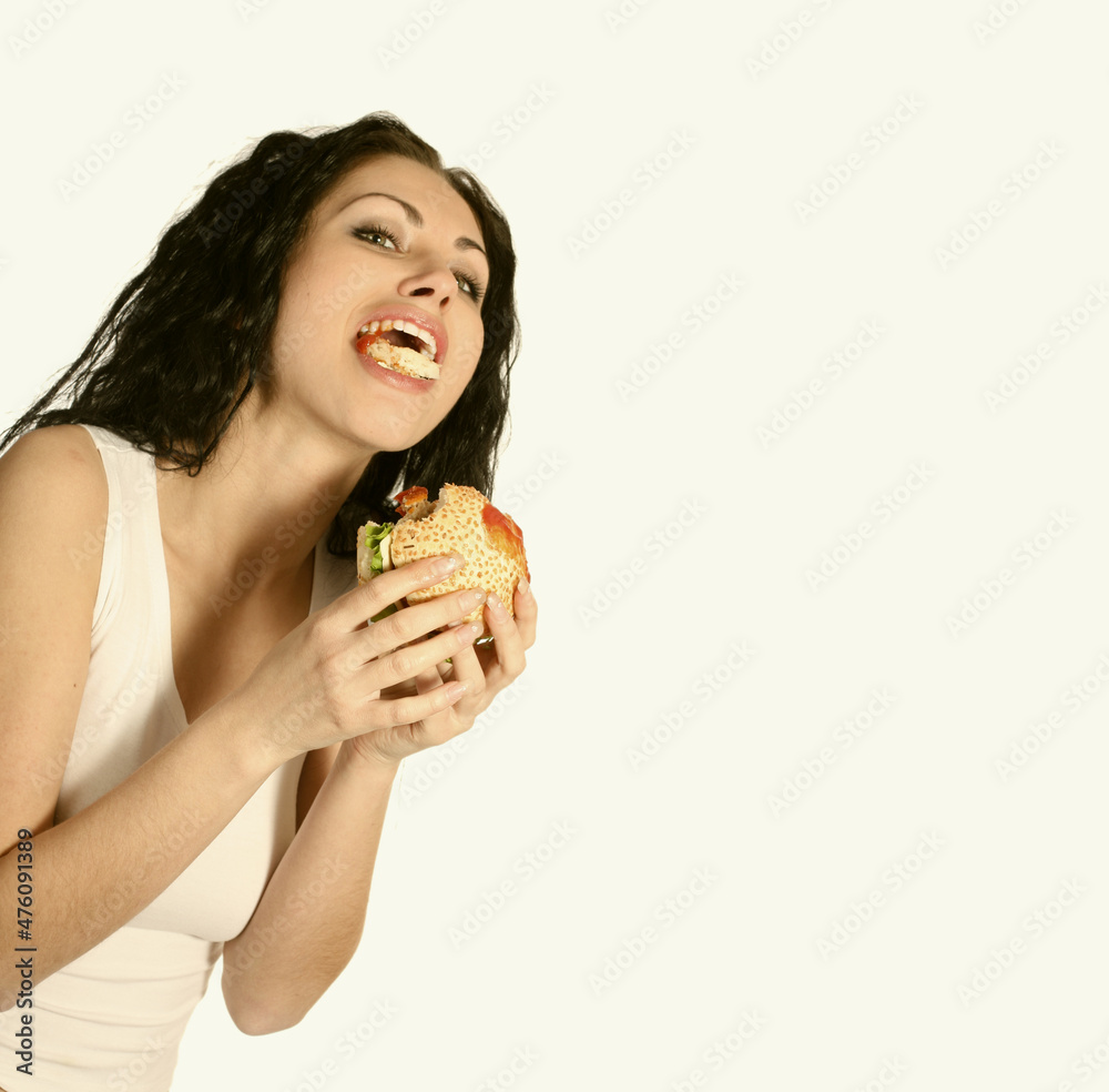 Beautiful carefree woman holdings and eating fast food hamburger. Beautiful carefree woman holdings and eating fast food hamburger.