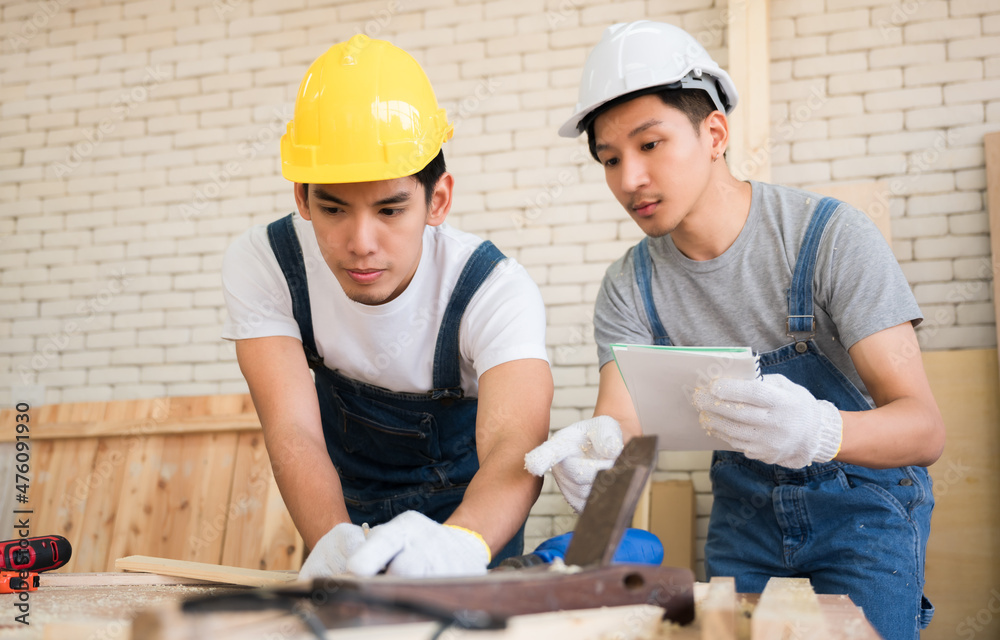 Professional two Asian carpenters wear safety helmets and work on woodwork in workplace at industrial. Professional two Asian carpenters wear safety helmets and work on woodwork in workplace at industrial.